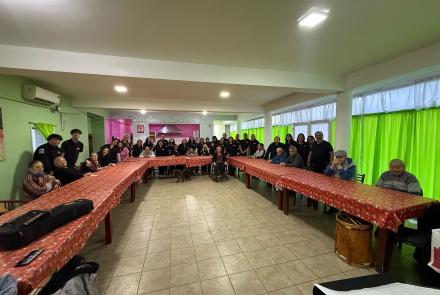 DI: Los y las integrantes de Bandada Coral están en uno de los salones del Hogar de Ancianos con las y los adultos mayores del lugar.